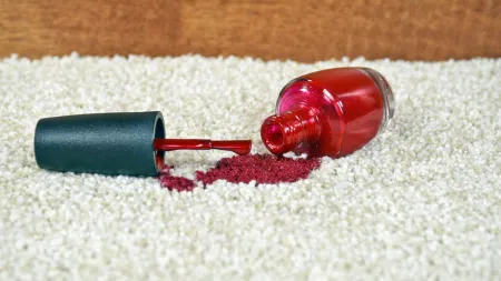 Spilled red nail polish on white carpet, creating a dramatic and colorful visual contrast.