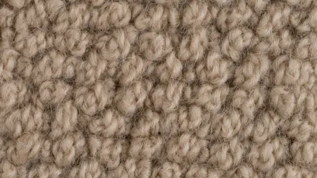 Close-up of textured beige wool fabric, showcasing its soft, cozy appearance and intricate weave patterns.