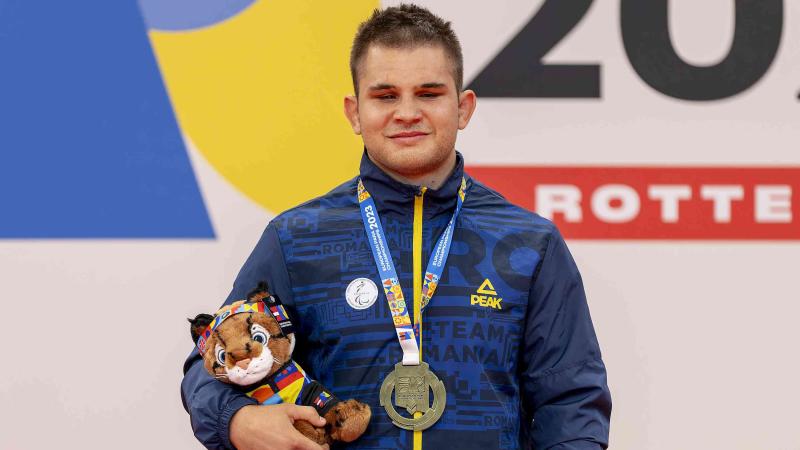 Florin Alexandru Bologa with his gold medal and mascot on the podium