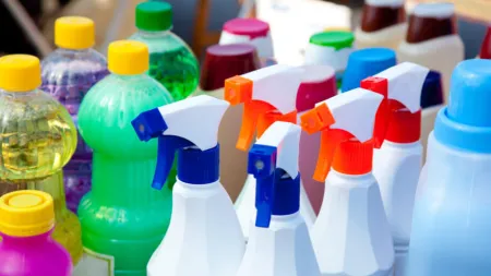Assorted cleaning products and spray bottles in vibrant colors displayed together.