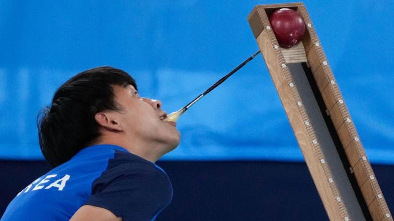 A Korean boccia player uses a a pointer with his mouth to position the ball on the ramp