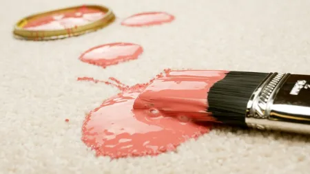 A spilled paint can with pink paint dripping on a soft carpet, showcasing a messy art project.