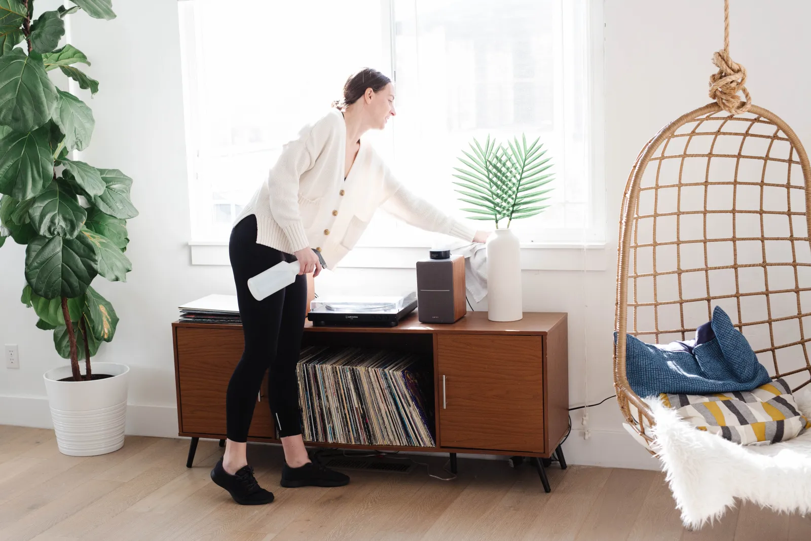 Woman dusting and cleaning her living room in her home