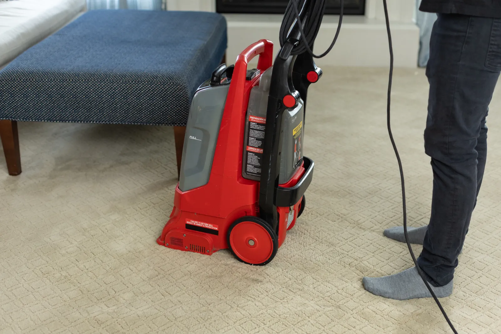 bottom half of a person standing behind a rental carpet cleaner trying to know how to clean carpets before moving out or in of a new place