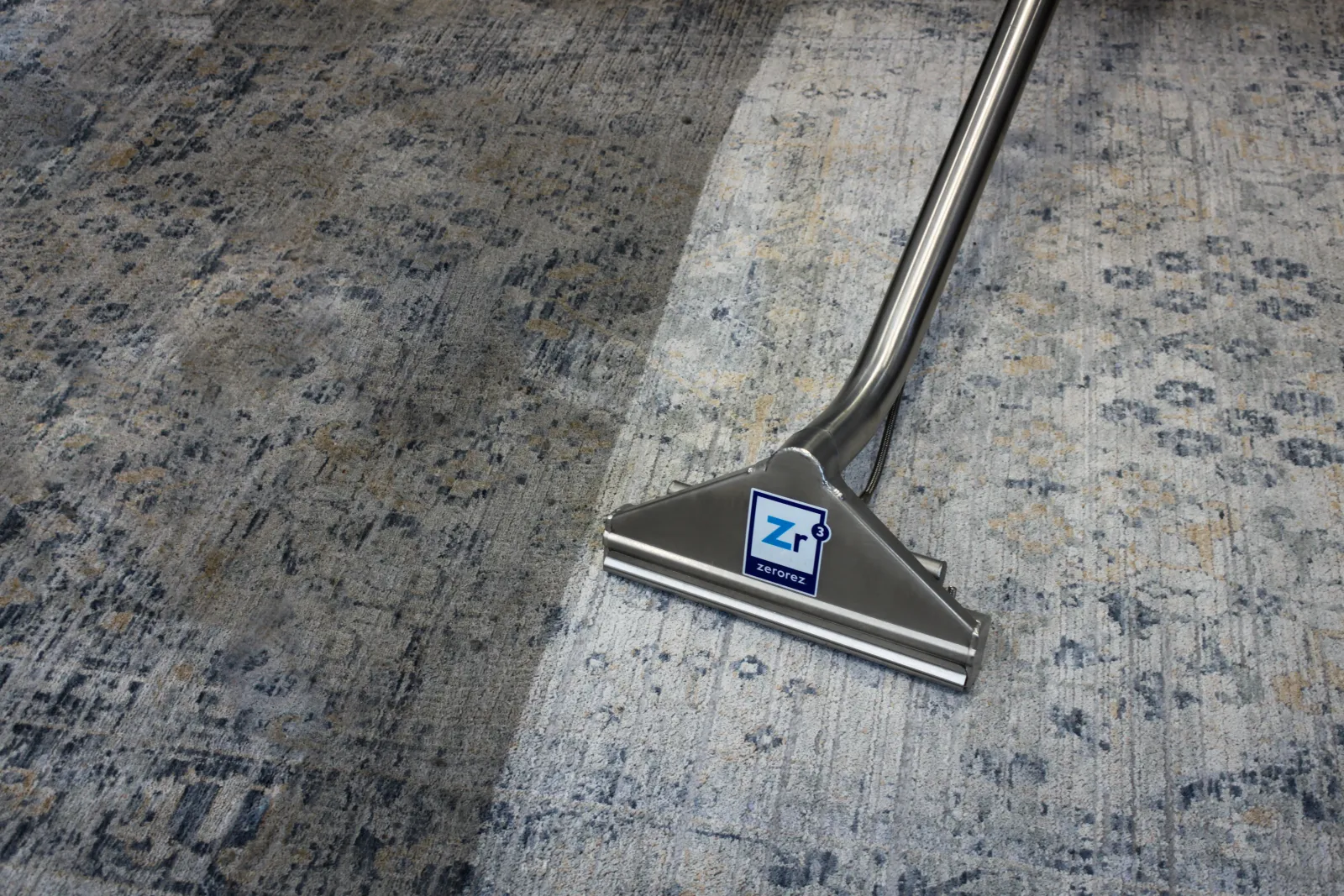 close up of a Zerorez Zr&trade; Wand on the clean side of a wool rug with the left side still visibly darker and dirtier