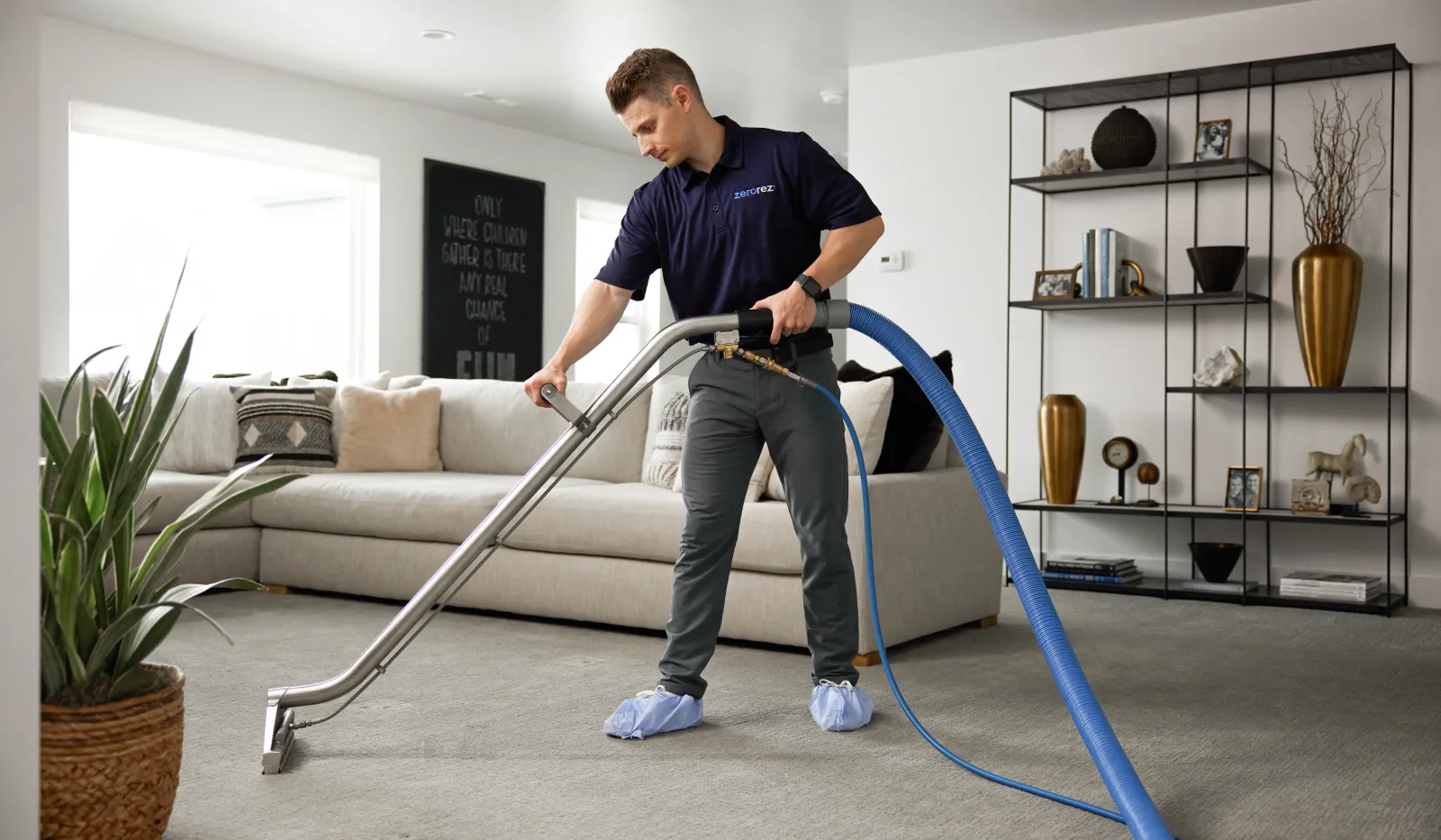 Professional cleaner using carpet cleaning machine in a modern living room with gray carpet and neutral decor